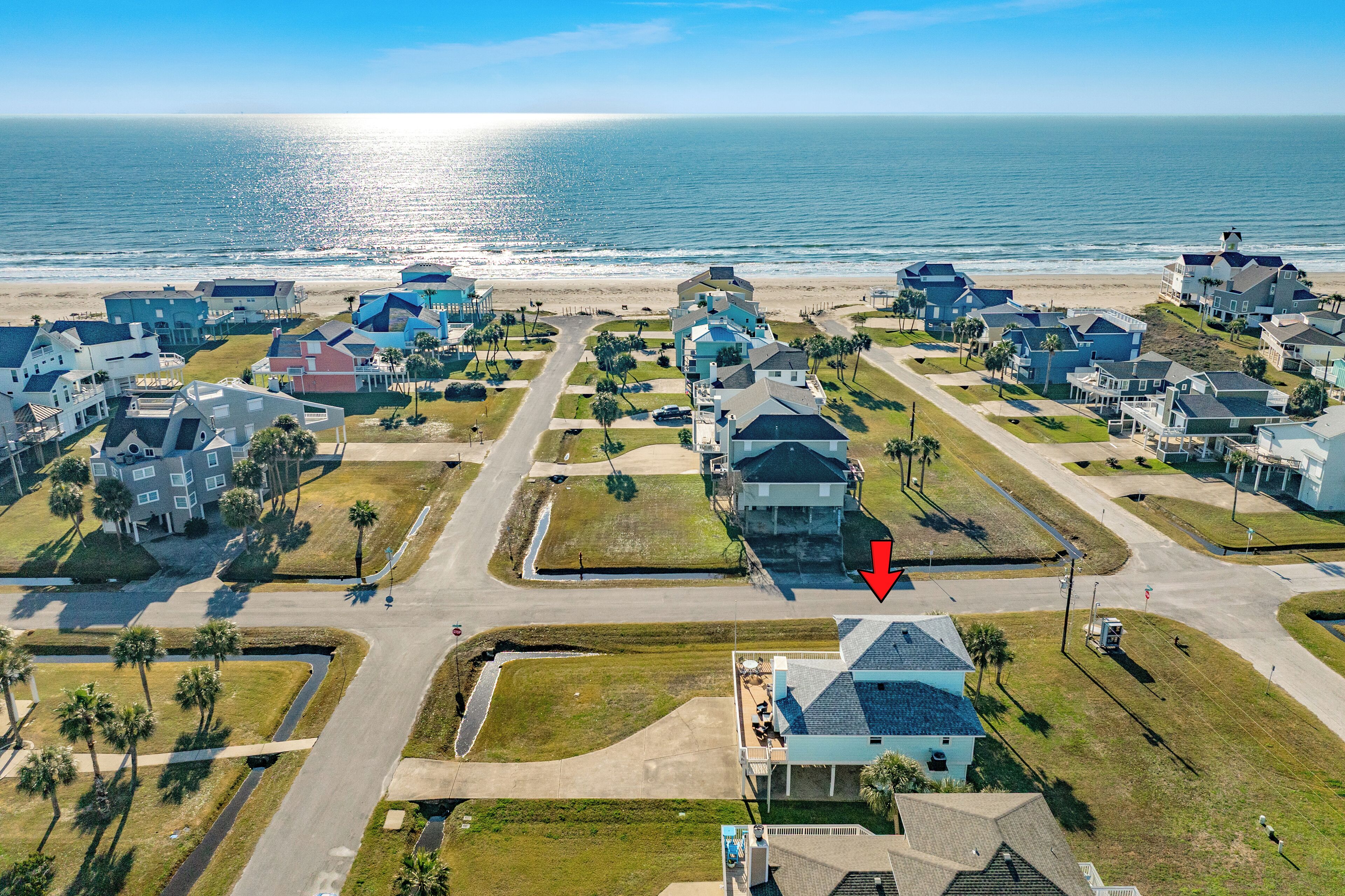 A coastal residential area with houses, a beach, and a road with a red arrow pointing to a specific location.