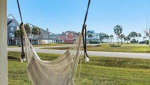 A hammock hanging outdoors with a residential area in the background. - Private Beachside Home, Perfect for Families, Updated Interior & Near Beach (Galveston)