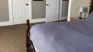 A bedroom with a bed, a ceiling fan, and two white doors.