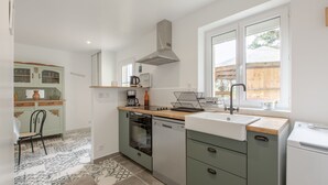 Cocina compacta con lavavajillas, horno y ventana con vistas al exterior.