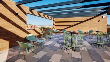 Una terraza en la azotea con suelo de madera, sillas verdes y vistas a la ciudad.