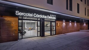 Ein moderner Hotel Eingang mit einem Schild, auf dem 'Sercotel Córdoba Delicias' steht.