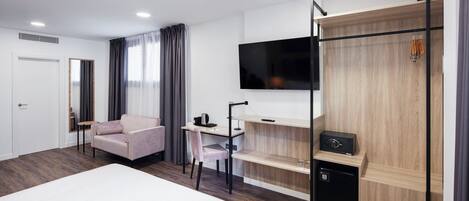 Habitación de hotel moderna con una cama grande, un escritorio con silla, un televisor montado en la pared y una caja fuerte.