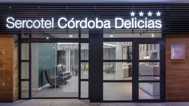 Der Eingang eines Hotels mit modernem Design, mit Glastüren und einem innenliegenden Sitzbereich.