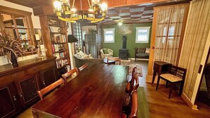 A dining room with a large wooden table, chairs, a chandelier, and a green wall. - Cozy cottage in the woods, sleeps 8, close to Olympic National Park and Lakes (Port Angeles)