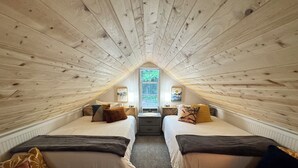 A cozy attic bedroom with two beds, a window, and a wooden ceiling. - Cozy cottage in the woods, sleeps 8, close to Olympic National Park and Lakes (Port Angeles)