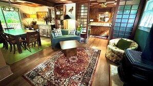 A cozy living room with a checkered ceiling, a dining area with a table and chairs, a green sofa, and a patterned rug. - Cozy cottage in the woods, sleeps 8, close to Olympic National Park and Lakes (Port Angeles)