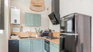 Eine moderne Küche mit türkisblauen Schränken, einem Edelstahlkühlschrank und einem eingebauten Backofen.