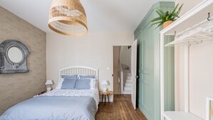 Ein Schlafzimmer mit Bett, Nachttischen, einem Spiegel und einer Pendelleuchte.