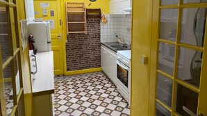 Een kleine keuken met gele wanden, een accentmuur van baksteen en een betegelde vloer.