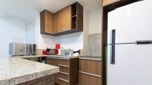 Une cuisine équipée d’un four à micro-ondes, d’un réfrigérateur, de meubles en bois et d’un plan de travail en granit.