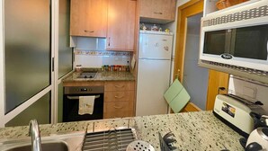 A compact kitchen with wooden cabinets, a built-in microwave, a toaster, and a sink.