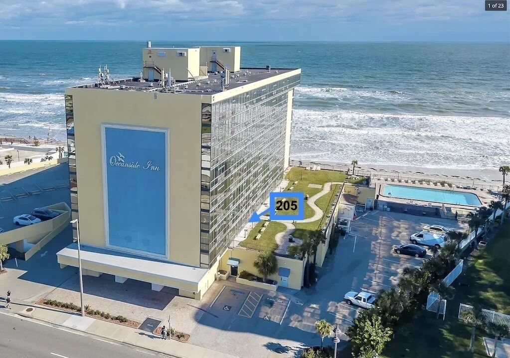 A hotel with a large glass facade, a pool, and a view of the ocean.