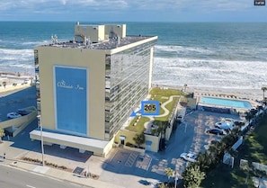 Ein Hotel mit einer großen Glasfassade, einem Pool und Meerblick.