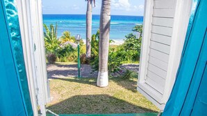 A view from a porch with a clear ocean and palm trees. - Malibu ocean View Studio (Montego Bay)