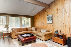 A living room with a sectional sofa, a coffee table, a side table, and a wooden wall panel. - Relaxing lakefront Getaway w/private dock, deck, washer/dryer (Bass Lake)