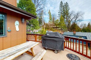 A wooden deck with a picnic table and a barbecue grill.