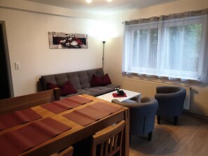 A modern living room with a grey sofa, a wooden coffee table, and a blue armchair.