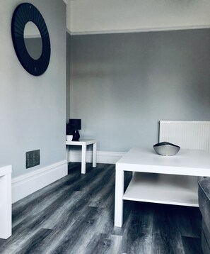 A room with a white table, a white chair, a small white side table, a black-framed mirror, and a white radiator. - Large four bedroom home in Bournemouth 
 (bournemouth)