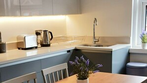 Une cuisine moderne avec une table à manger en bois, des meubles de rangement gris et une petite plante en pot.
