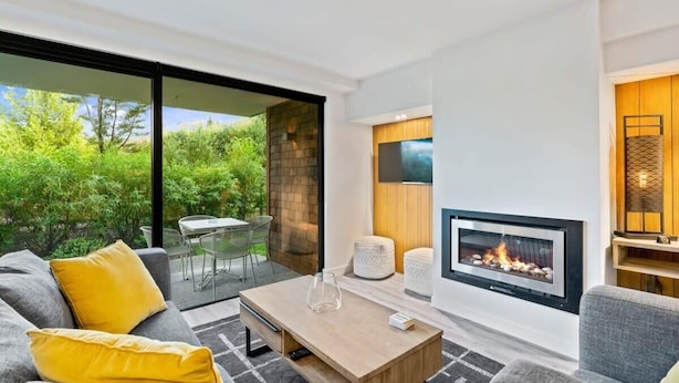 Una sala de estar moderna con chimenea, un sofá, una mesa de centro y un televisor.