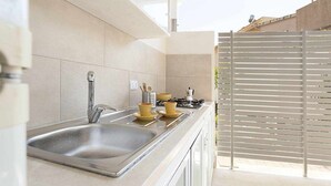A modern kitchen with a stainless steel sink, a gas stove, and a window with blinds.