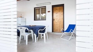 A small dining area with a table and chairs, a wooden door, and a blue chair. - (B67) Cozy house with veranda 150 mt from the sea (Marina Di Modica)