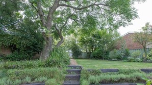 Un vialetto di giardino che conduce a una casa con un muro in mattoni e una recinzione in legno.