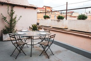 A round table with four chairs, a glass top, and two wine glasses on a rooftop terrace. - Apartment with terrace between Termini Station and Opera House (Roma)