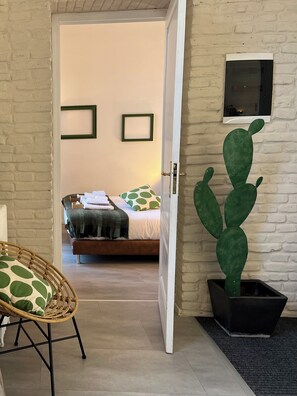 A room with a bed, a wicker chair, a cactus, and a white brick wall. - Apartment with terrace between Termini Station and Opera House (Roma)