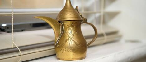 Una tetera de bronce con diseños intrincados sobre un alféizar.