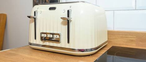 A vintage white toaster on a wooden countertop with a modern induction cooktop below it.