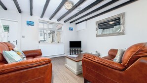 A living room with two brown leather sofas, a wooden coffee table, a flat-screen TV, and a window with blinds. - 5 Ivy Yard (Whitby)