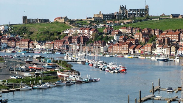 A harbor with boats docked, surrounded by residential buildings and a historic church in the background. - 5 Ivy Yard (Whitby)