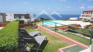 Terraza en la azotea con piscina, zona de estar y vista al océano.