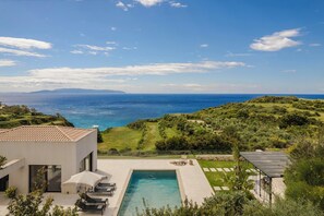 Una villa moderna con piscina, area salotto esterna e vista sul mare.