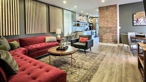 A modern living room with a red sofa, a round coffee table, and a kitchen in the background. - Swanky Suite @ Bungalou + Bourbon Bar + Gameyard (Louisville)