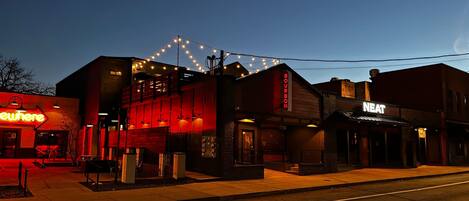 A building with a neon sign reading 'Bourbon' and another sign 'Neat' on the side.