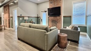 A living room with a sofa, a chair, a television, and a fireplace.
