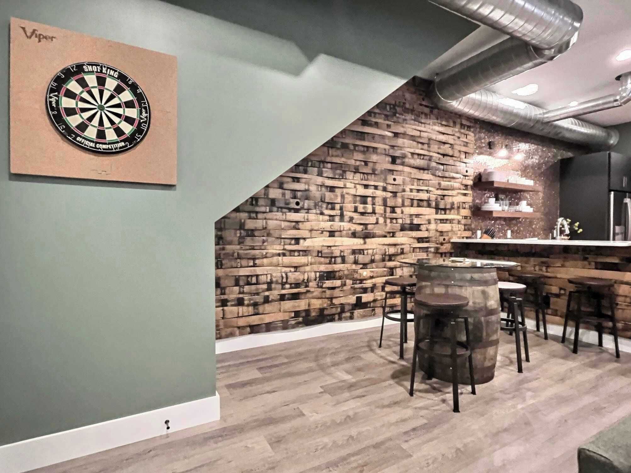 A room with a dartboard, a brick wall, a bar area, and a kitchen.