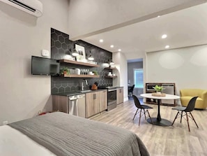 A modern kitchen with built-in appliances, a dining area with a round table and chairs, and a separate living space with a sofa.