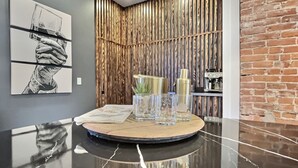 A modern interior with a marble countertop, a round wooden table, and a vertical wooden panel wall.