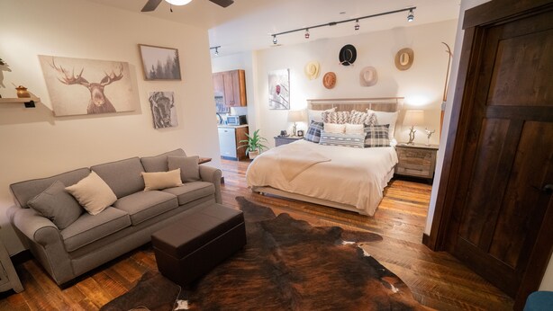 Una sala de estar acogedora con un sofá gris, un tapete de piel grande y piso de madera.