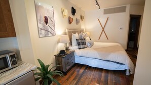 Un dormitorio con cama, mesita de noche, lámpara y una colección de sombreros colgada en la pared.
