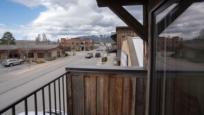Un balcón con vista a una calle, edificios y montañas a lo lejos.