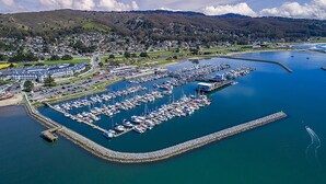 An aerial view of a marina with numerous boats docked, surrounded by a residential area and hills in the background. - Nantucket Penthouse - walk to restaurants, beaches, activies & so much more (Half Moon Bay)