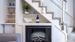 A staircase with a modern design, a fireplace with logs, and a shelf with decorative items. - Nantucket Penthouse - walk to restaurants, beaches, activies & so much more (Half Moon Bay)