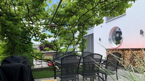 A patio area with outdoor furniture, a covered grill, and a garden hose.