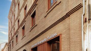 A brick building with a sign for 'Sercotel Granada Suites' indicating a hotel or accommodation.