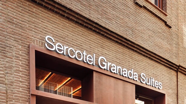 Un edificio de ladrillo con un letrero que dice "Sercotel Granada Suites".